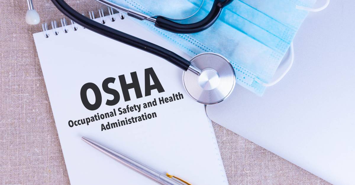 An OSHA notepad and clipboard rest on a desk, surrounded by a healthcare mask, stethoscope, and a fountain pen.